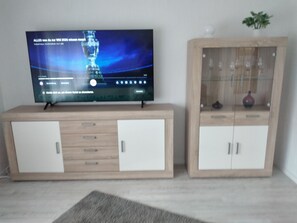 Et fladskærms-tv på et træskab med et glasmontreskab ved siden af.