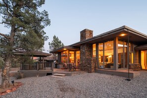 Una casa moderna con chimenea de piedra, ventanas amplias y un patio con mobiliario exterior.
