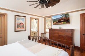 Une chambre à coucher avec un lit, une commode et une grande fenêtre donnant sur les montagnes.
