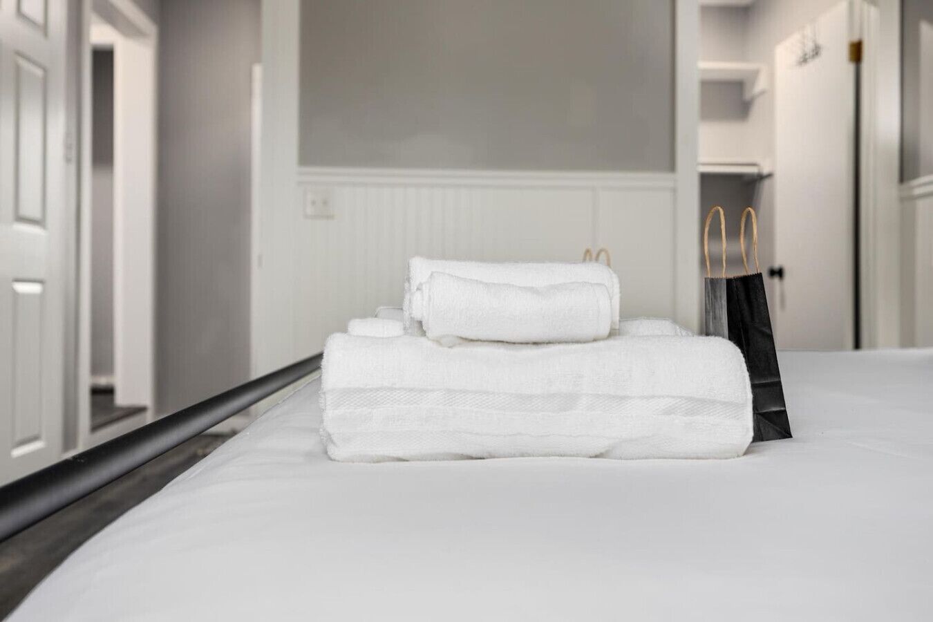 A neatly made bed with white linens and a black bag on it.