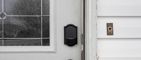 Una puerta blanca con un panel de vidrio, un portero automático y un timbre.
