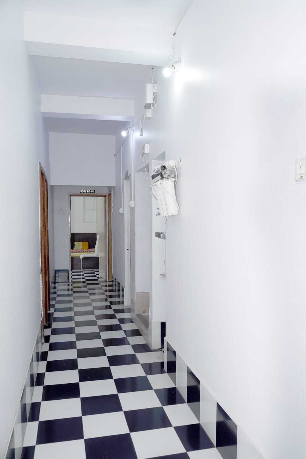 A narrow hallway with a checkered floor leading to a room labeled "ROOM NO-11".