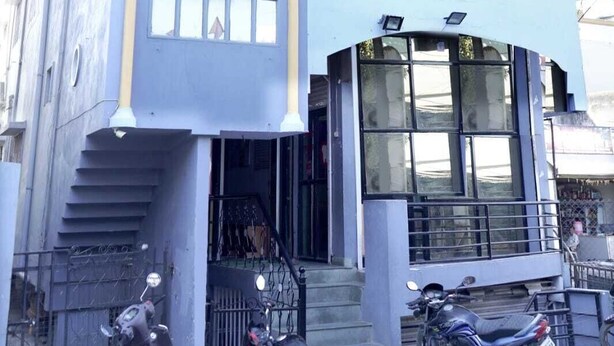 Un edificio de varios pisos con un estilo arquitectónico moderno, que cuenta con grandes ventanales y una entrada destacada con escalones.