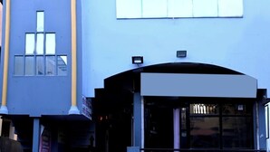 Un edificio con fachada azul, entrada curva y un cartel.