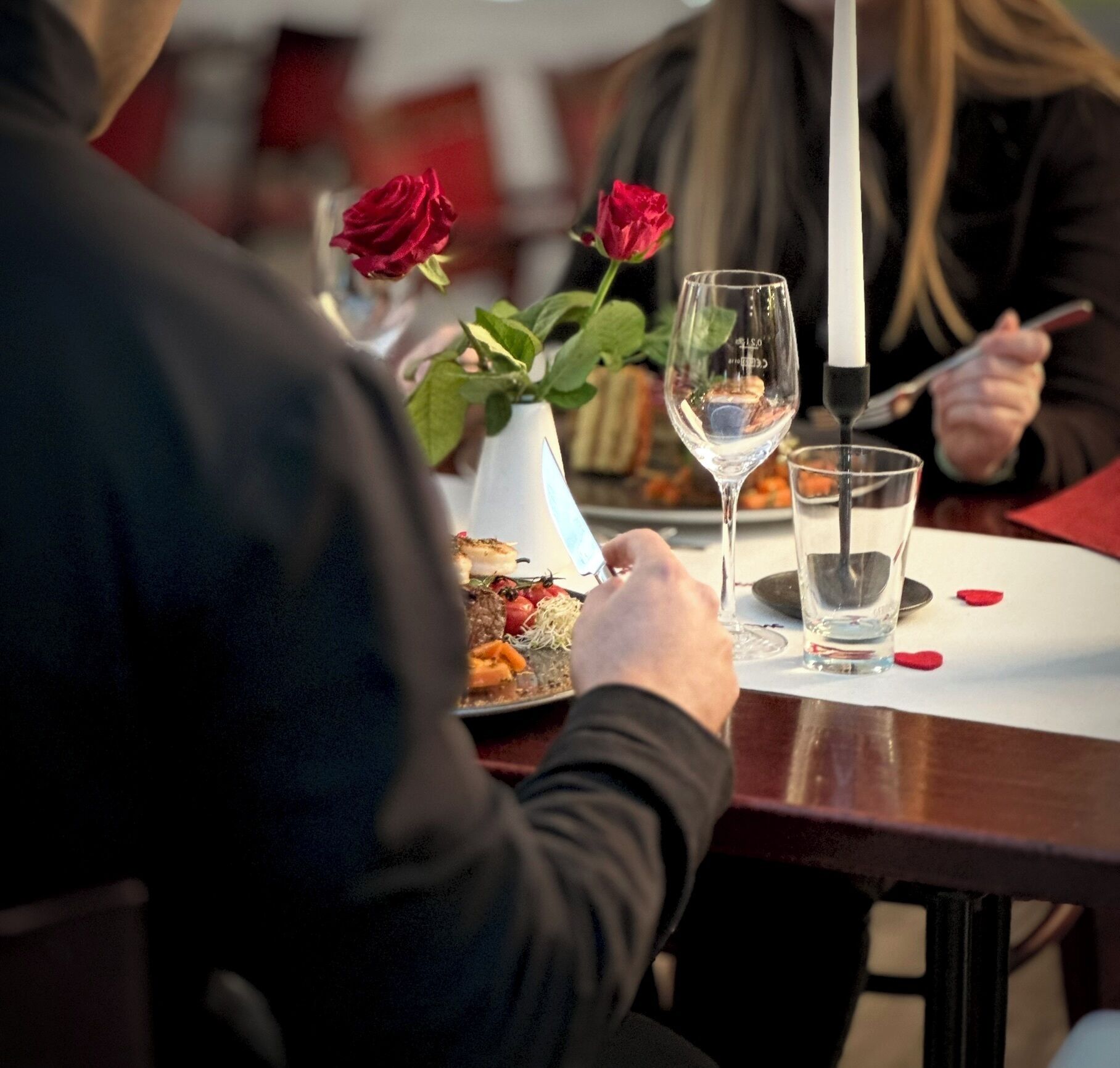 A dining table with a plate of food, a glass of water, and a wine glass.