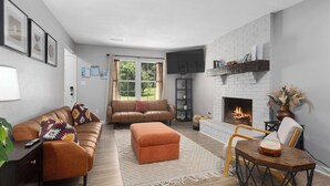 Un salon avec un canapé, un pouf et une cheminée.