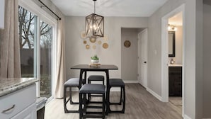 Une cuisine moderne avec un coin repas, comprenant une table en bois, quatre chaises et un luminaire suspendu.