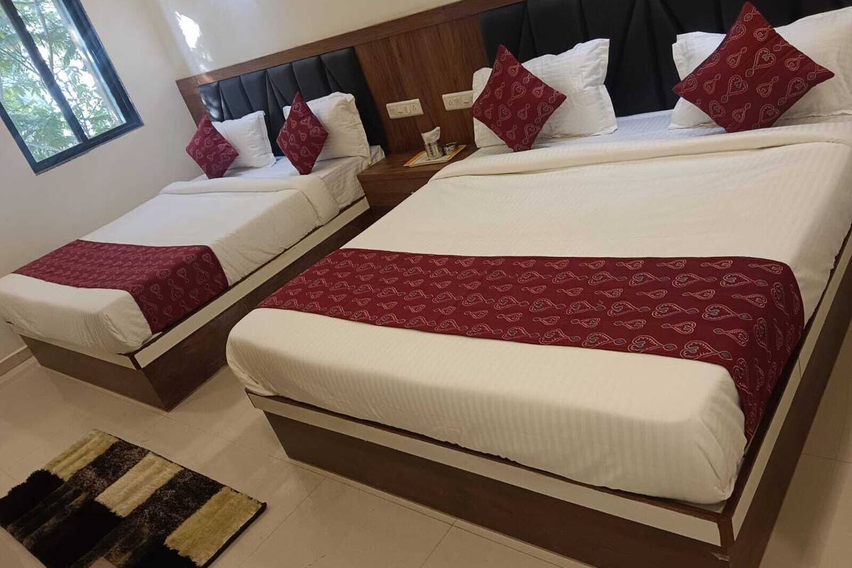 Une chambre d’hôtel avec deux lits, chacun étant équipé de draps blancs et d’une couvre-lit à motifs rouges.