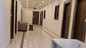 Un corridoio con una reception, una poltrona e porte che danno accesso alle camere.