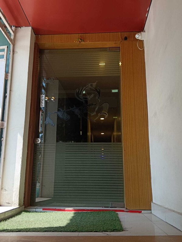 A modern building entrance with a glass door, a wooden frame, and a red awning.
