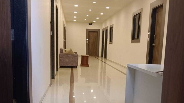 Corridoio di un hotel con una poltrona, una reception e diverse porte.