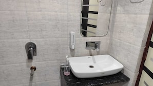 Ein Badezimmer mit Waschbecken, Spiegel, Seifenspender und Handtuchhalter.