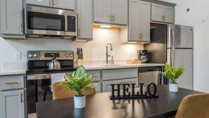 A modern kitchen with stainless steel appliances, a dark countertop, and two potted plants.
