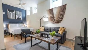 A modern living room with a bed, sofa, coffee table, and TV.