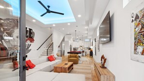 A spacious living area with a high ceiling, a ceiling fan, a large TV, and a staircase leading to another level. - Luxury Nashville retreat w/ rooftop lounge & pool (Nashville)
