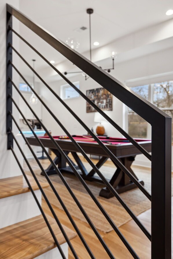 A modern interior with a wooden staircase, a pool table, and a dining area. - Luxury Nashville retreat w/ rooftop lounge & pool (Nashville)