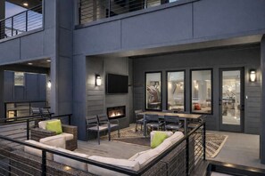 A modern outdoor patio with a fireplace, seating, and a dining area. - Luxury Nashville retreat w/ rooftop lounge & pool (Nashville)