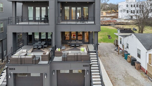 A modern two-story building with a flat roof, large windows, and a covered outdoor seating area. - Modern and sleek unit near Downtown with billiards (Nashville)