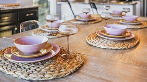 A dining table set with purple bowls and wine glasses on woven placemats.