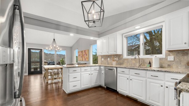 A modern kitchen with white cabinets, a large island, and a dining area with a table and chairs.