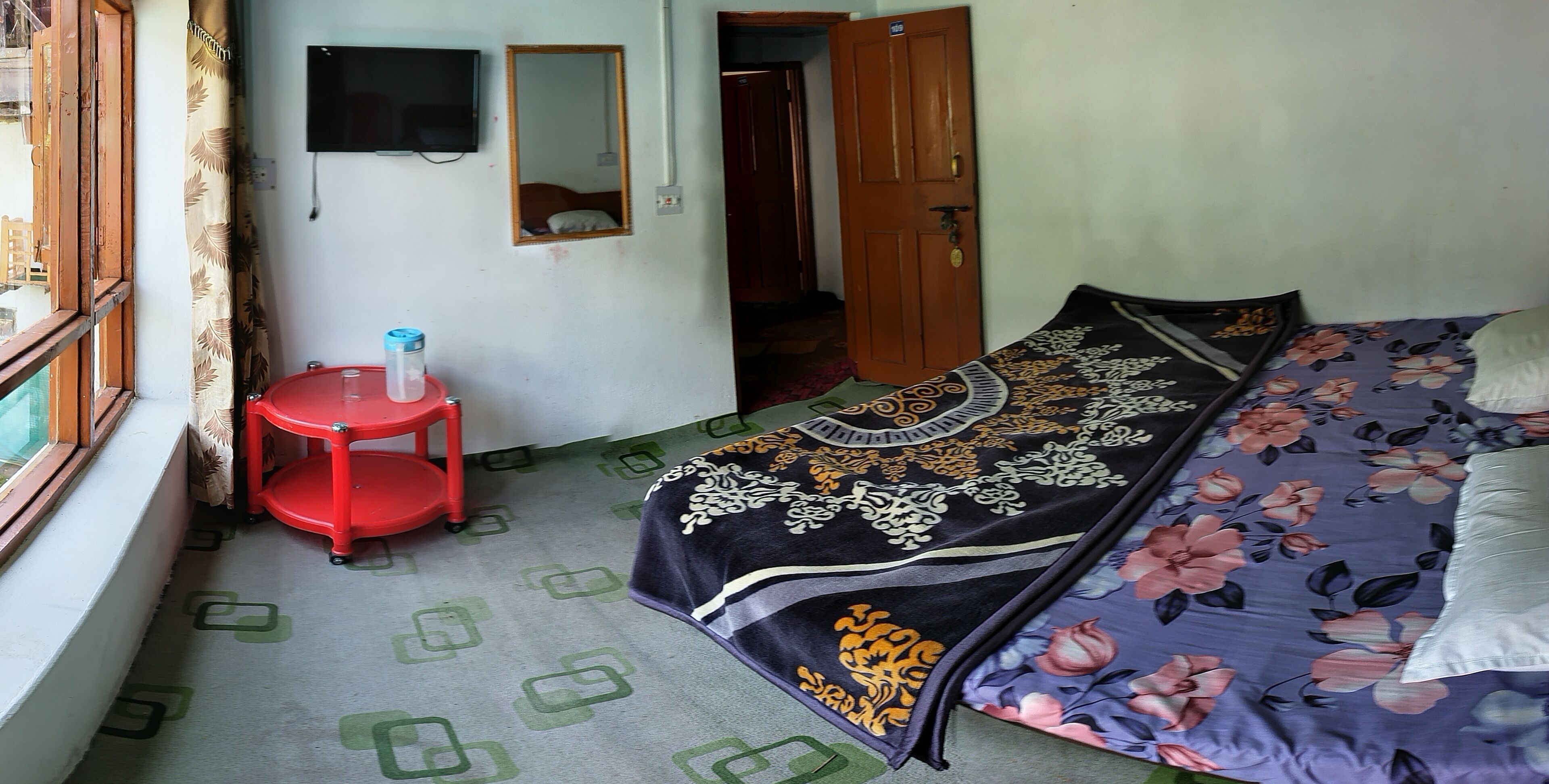 Un dormitorio con una cama, un taburete rojo, un espejo y una puerta.