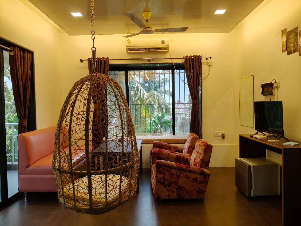 A living room with a hanging chair, a sofa, a television, and a small table.