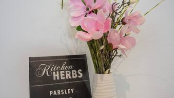 Eine weiße Vase mit rosa Blumen und einem Schild, auf dem Küchenkräuter aufgeführt sind.