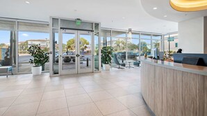 A modern reception area with a glass door entrance, potted plants, and a reception desk. - Seagrove Beachfront Condo with Incredible Views (Santa Rosa Beach)