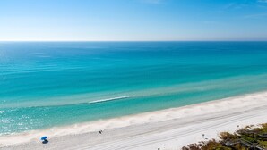 A beach with clear turquoise water, a sandy shore, and a blue umbrella. - Seagrove Beachfront Condo with Incredible Views (Santa Rosa Beach)