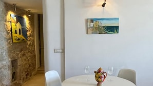 Un área de comedor con una mesa redonda, sillas blancas, un tapete de piso negro y un cuadro en la pared.