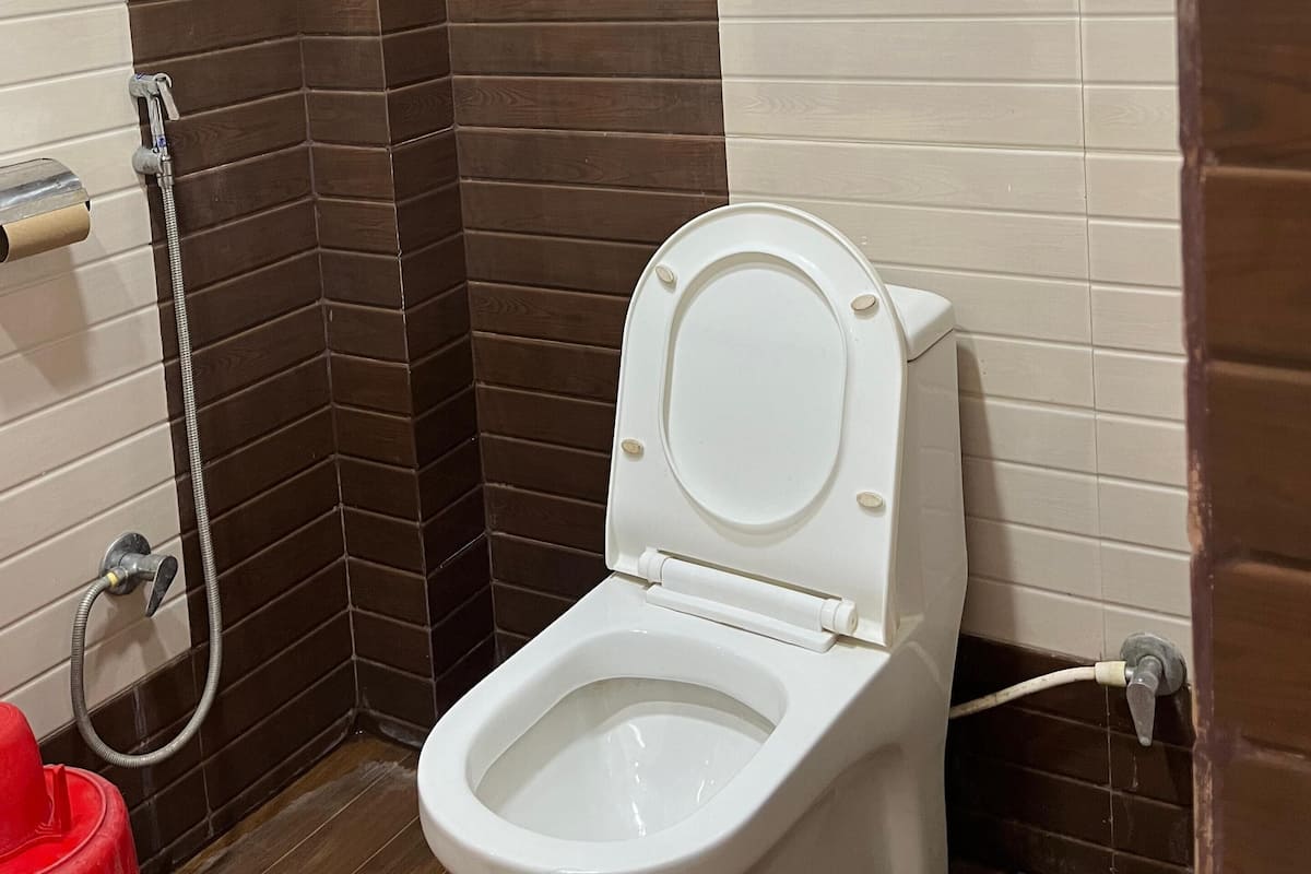 A bathroom with a white toilet, a shower area, and a wall-mounted air conditioning unit.