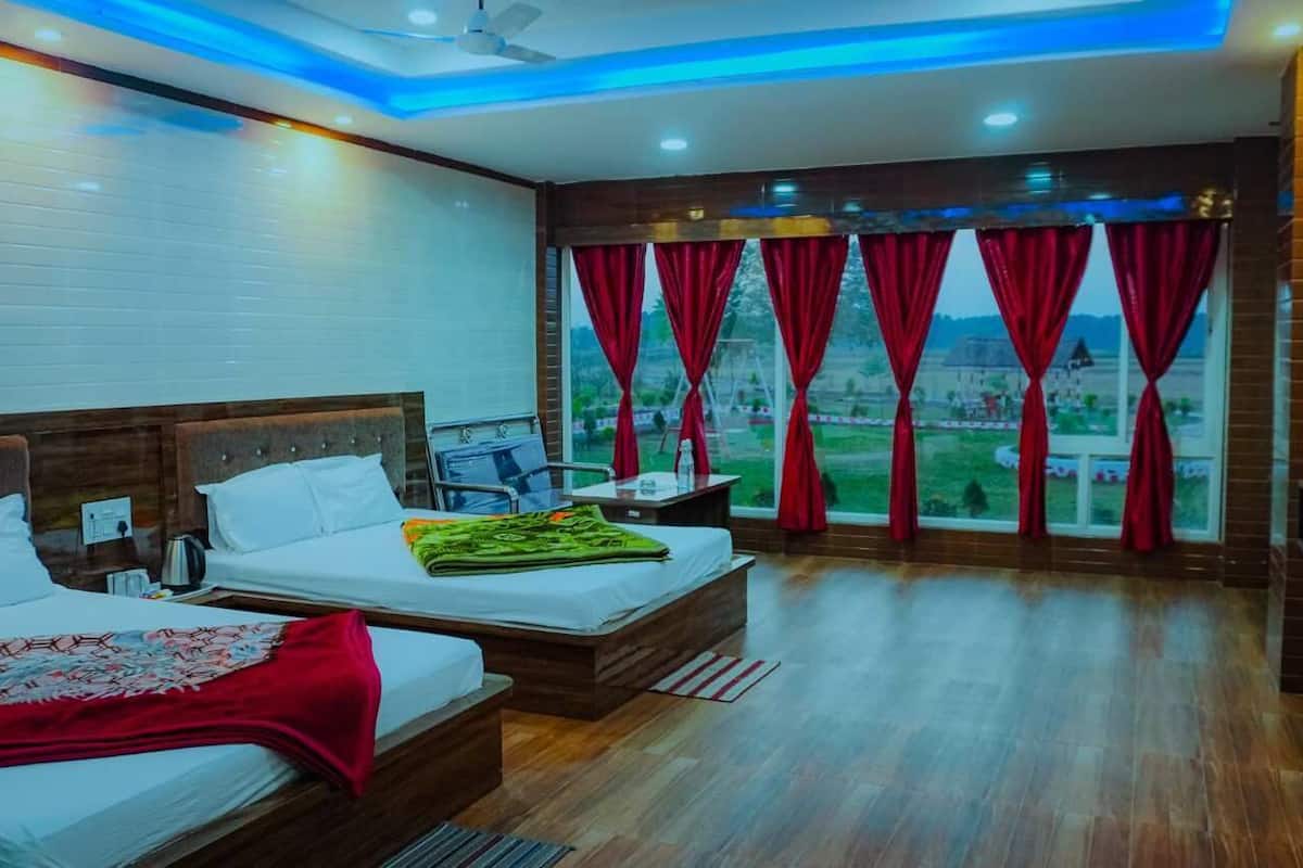 A hotel room with two beds, a desk, and a view of the countryside.