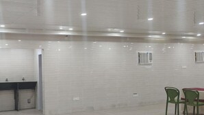 A clean, modern room with white tiled walls, a sink, and a table with chairs. - Amantran Hotel & Resort (Alipurduar)
