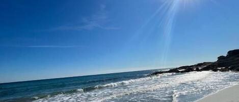 Na praia, areia branca, guarda-sóis