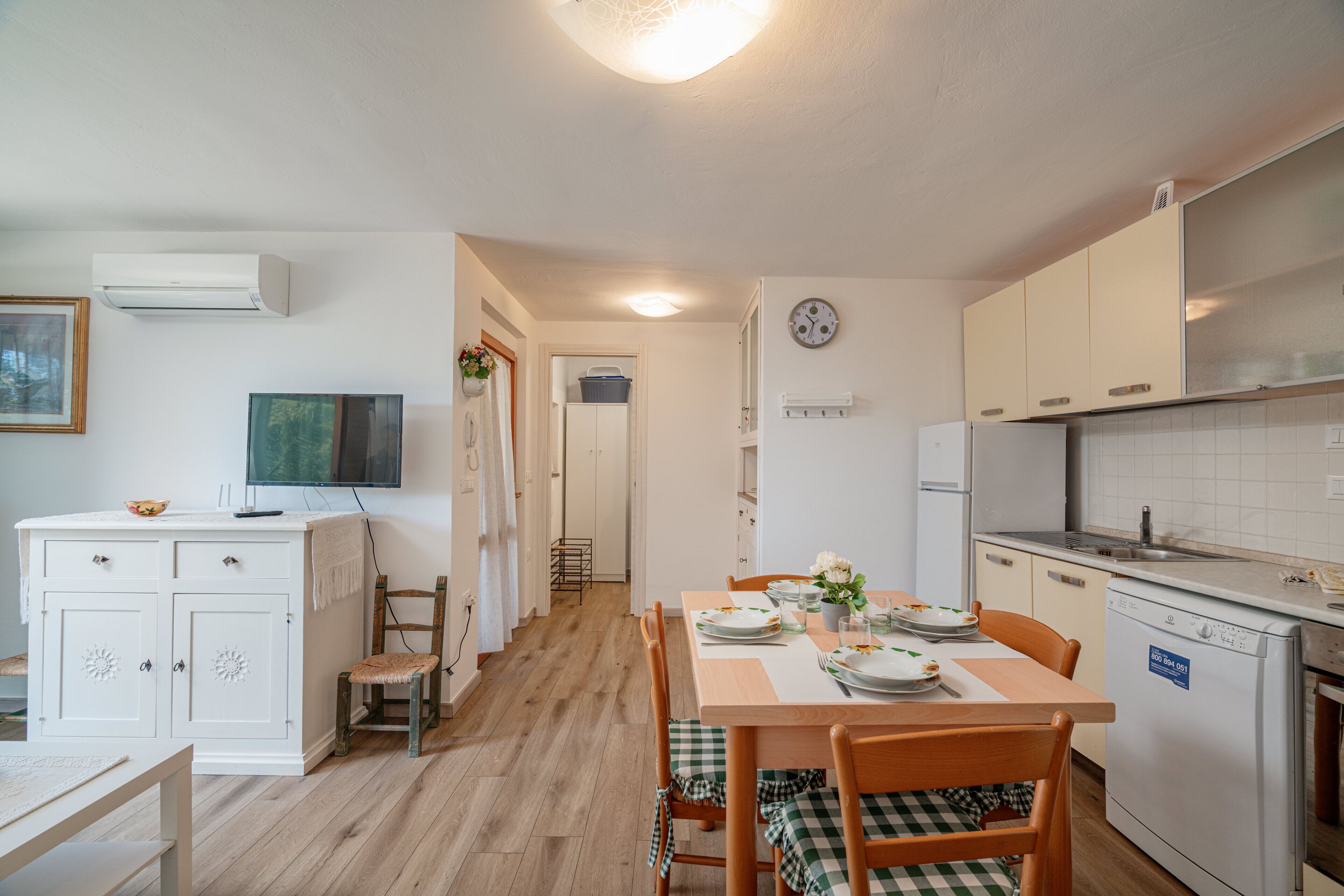 A compact kitchen with white cabinets, a dining table set for two, and a built-in dishwasher.