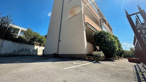 A multi-story building with a flat roof, a balcony, and a gated entrance. - Apartman Portos (Crikvenica)