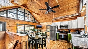Una cocina amplia con pisos de madera, gabinetes blancos, una isla grande y un comedor con mesa y sillas.