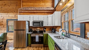 Una cocina moderna con paredes de madera, un refrigerador de acero inoxidable, un microondas y un lavamanos.