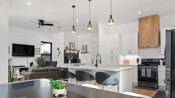 A modern kitchen with a central island, black chairs, white cabinets, and a black refrigerator. - Downtown ATX - Unit A | Modern Home | Pool (Austin)