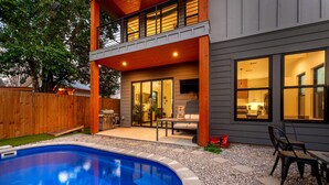 A two-story house with a swimming pool, a covered patio, and a visible kitchen area. - Downtown ATX - Unit A | Modern Home | Pool (Austin)