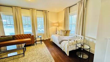 A hotel room with a bed, a sofa, a small table, and a lamp.