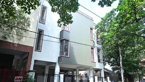 Un edificio residencial de varios pisos con techo plano, un balcón en el segundo nivel y una entrada con portón.