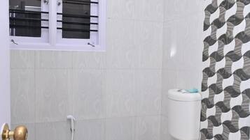 Un baño pequeño con inodoro, ducha y ventana con persianas.