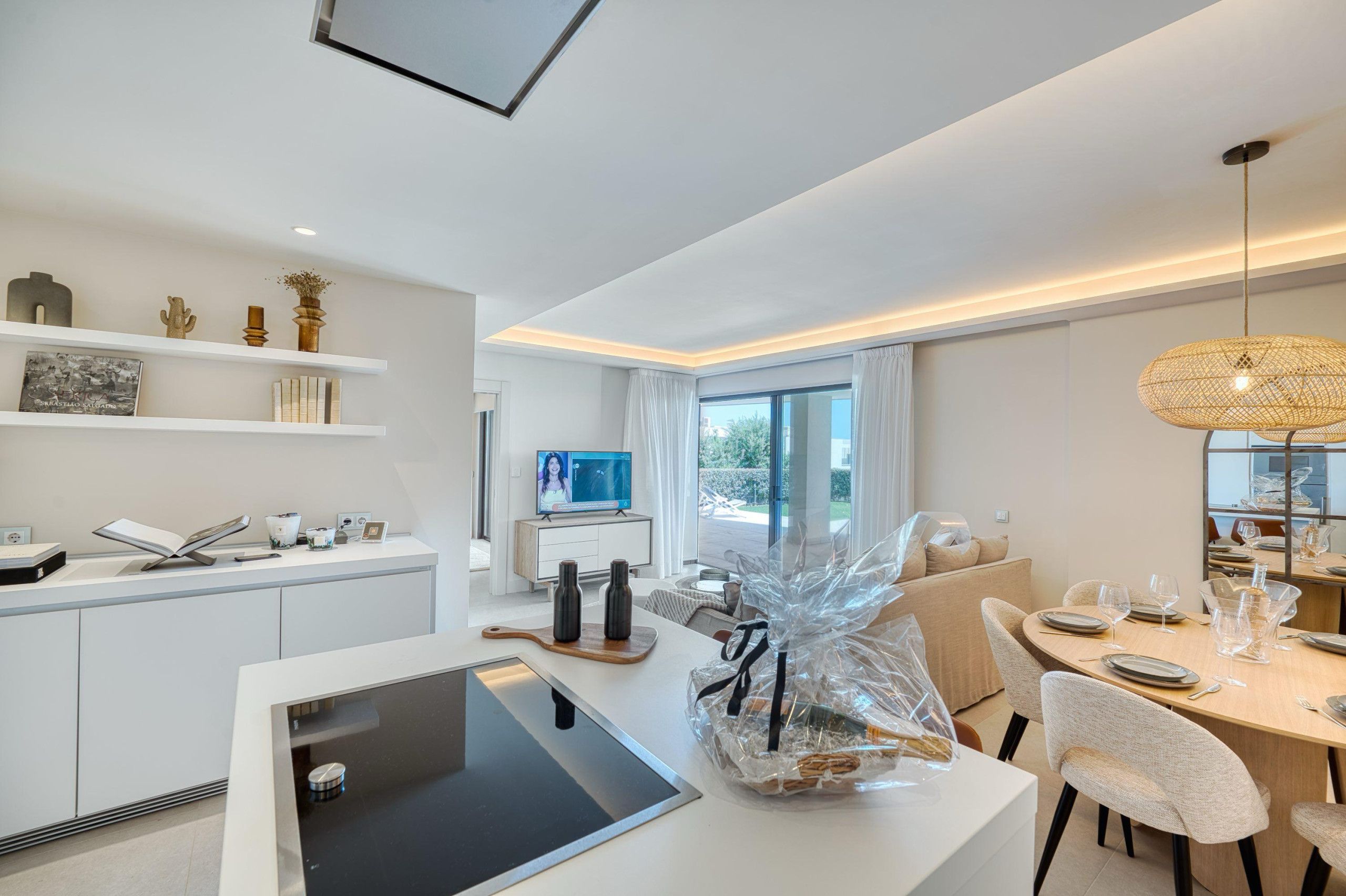 A modern kitchen with white cabinetry, a built-in oven, and a dining area with a table set for two.