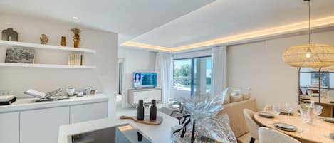A modern kitchen with white cabinetry, a built-in oven, and a dining area with a table set for two.