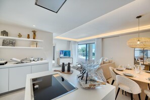 A modern kitchen with white cabinetry, a built-in oven, and a dining area with a table set for two.