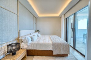 Un dormitorio moderno con una cama grande, una mesita de noche con lámpara y vistas al balcón.