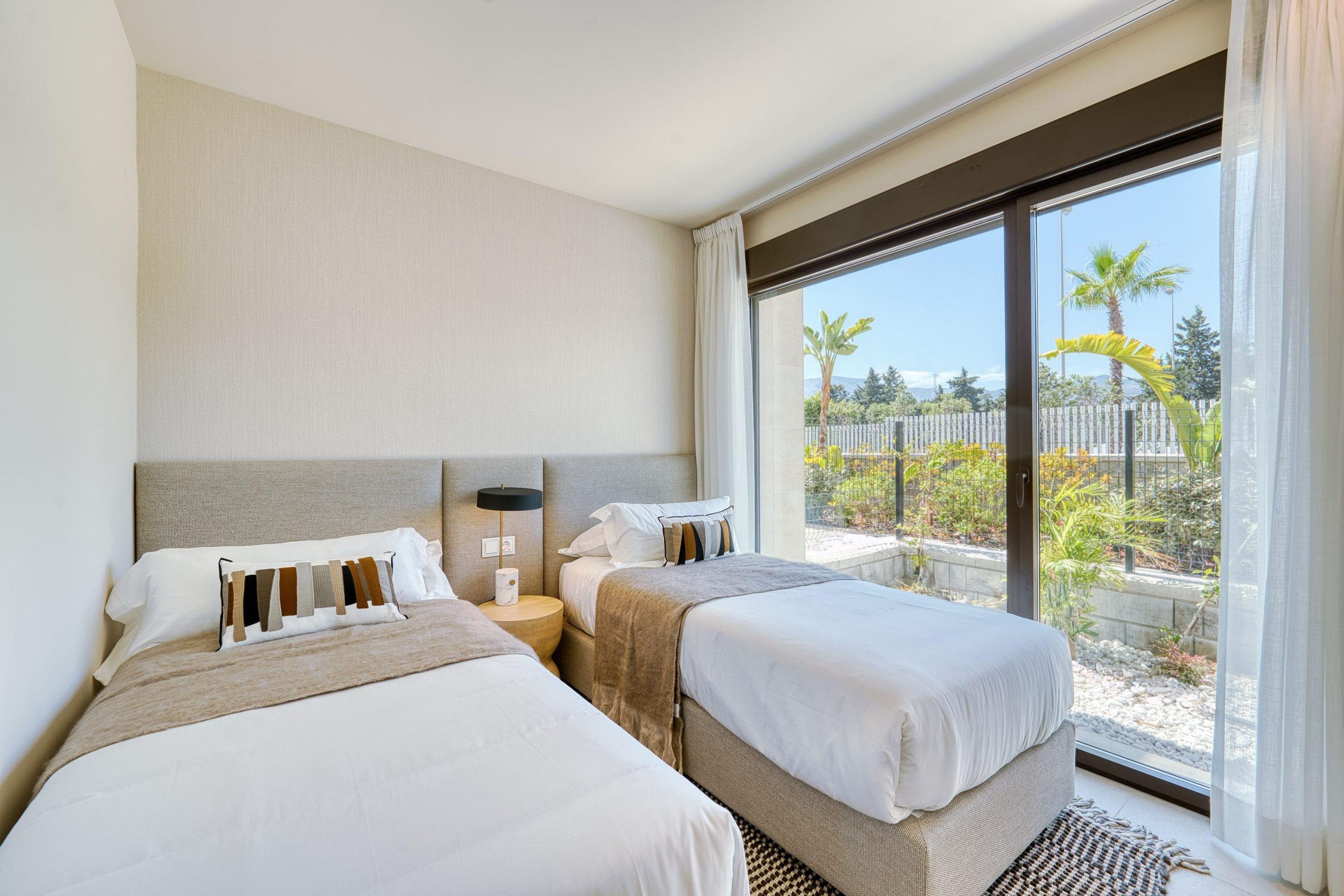 Quarto de hotel com duas camas, uma janela grande e vista para o exterior.