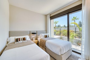 A hotel room with two beds, a large window, and a view of the outdoors.