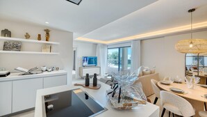 A modern kitchen with white cabinetry, a built-in oven, and a dining area with a table set for two. - 3001 Velaya Beachfront Luxury Apartment (Estepona)